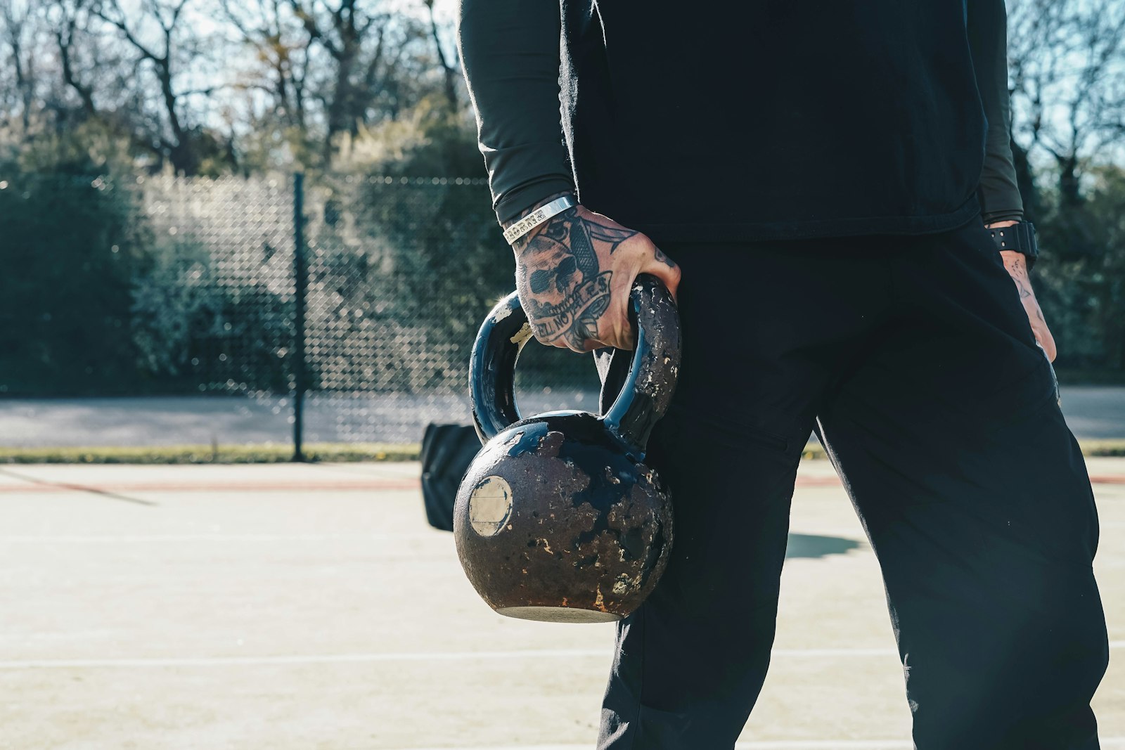 Man holding a kettlebell for goblet squats outdoors