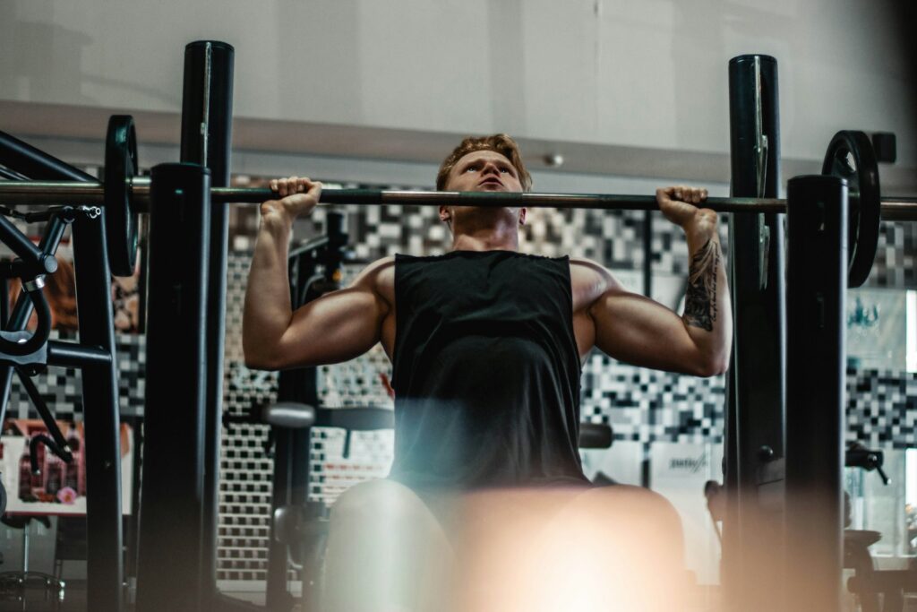 Man pressing a barbell overhead in a gym
