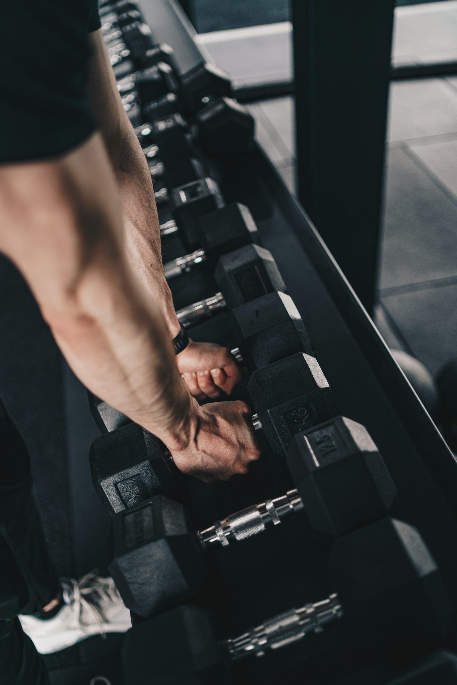 Man picking up dumbbells from a rack